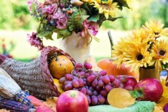 Színes gyümölcsök és virágok egy asztalon, tavaszi hangulatban.