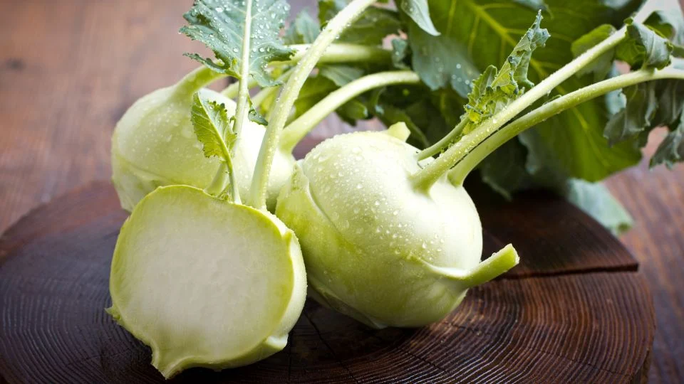 Friss karalábék vízcseppekkel, egy szelet levágva, fából készült felületen.