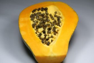 Félbevágott papaya, sárga húsával és fekete magjaival, friss gyümölcs.
