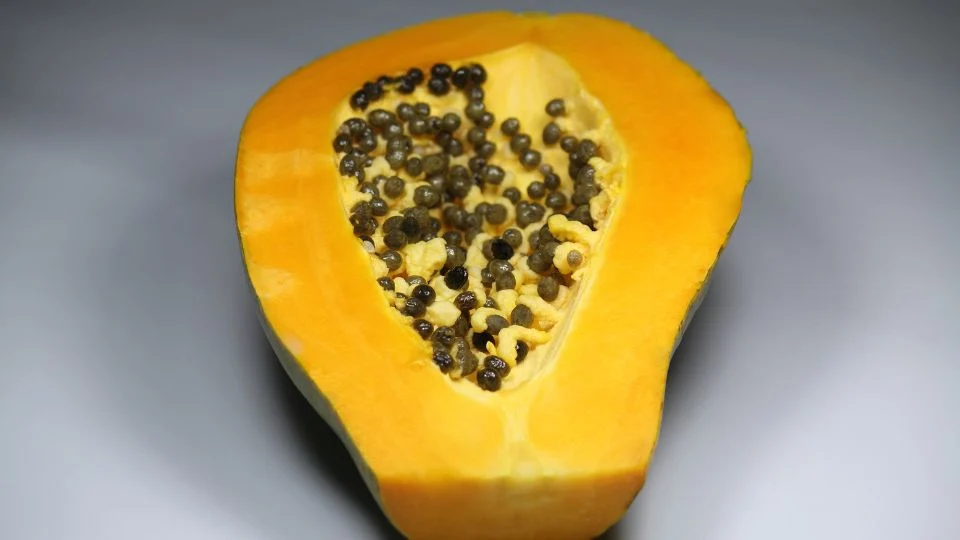 Félbevágott papaya, sárga húsával és fekete magjaival, friss gyümölcs.