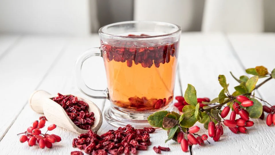 Friss borbolya tea és gyümölcsök Egy üveg borbolya teát mutat, mellette friss borbolya bogyók és szárított gyümölcsök.