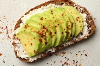 Avokádós kenyér, krémsajttal és fűszerekkel, ízletes és egészséges étkezés.