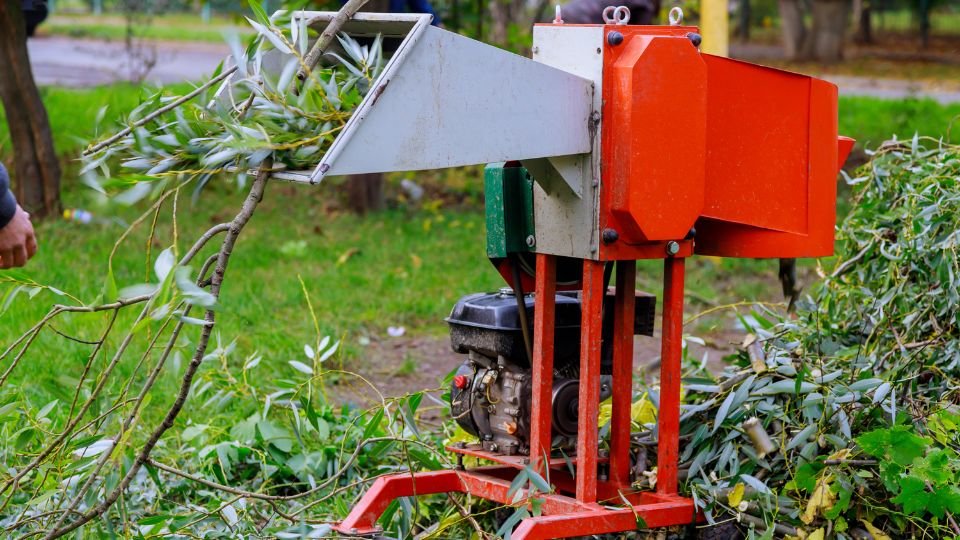 Kerti ágaprító működés közben, zöld levelekkel teli ágakat aprít a motoros gép.