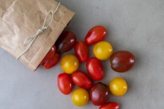 Friss koktélparadicsomok színes keveréke papírzacskóból kiborulva.