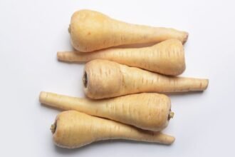 Friss pasztinákok, különböző méretűek és formájúak, fehér háttér előtt.