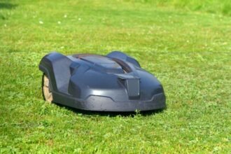 Egy robotfűnyíró zöld pázsiton, napfényben dolgozik.