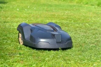 Egy robotfűnyíró zöld pázsiton, napfényben dolgozik.