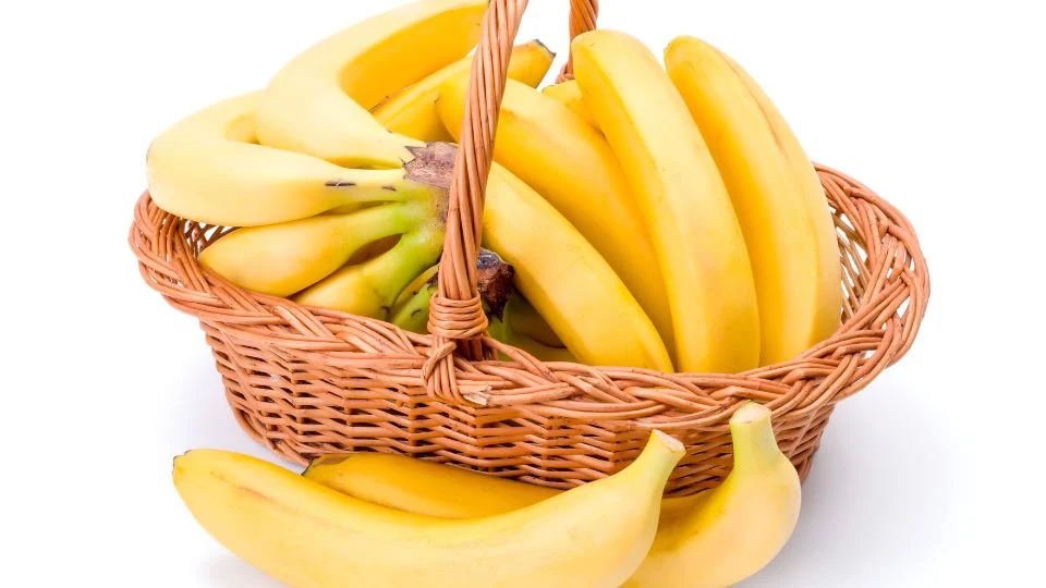 Friss, sárga banánok egy fonott kosárban, szép elrendezésben.