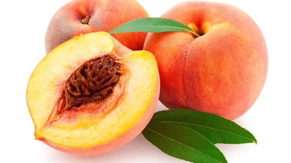 Érett, zamatos barackok, egy félbevágott gyümölcs és friss levelek.