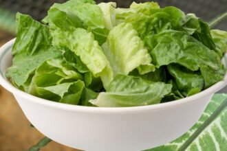 Friss, ropogós fejes saláta levelek fehér tálban, zöld színben.