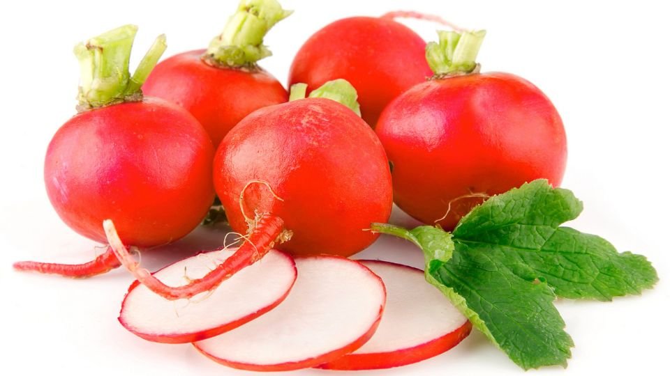 Friss, piros retekek zöld levelekkel, néhány szeletelve.