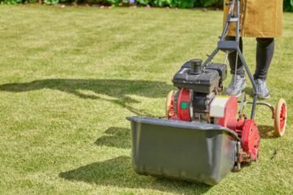 Egy személy gyepszellőztetőt használ az őszi kertben, a fű szép zöld.