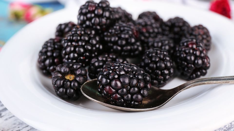 Friss szeder gyümölcsök egy fehér tányéron, fényes és ízletes megjelenéssel.