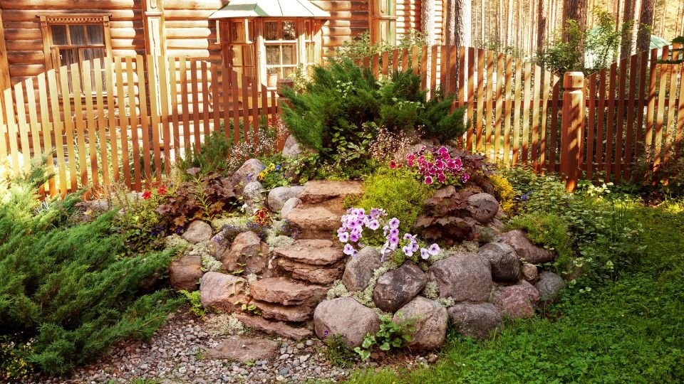 Sziklakert virágokkal és lépcsőkkel, zöld növények között.