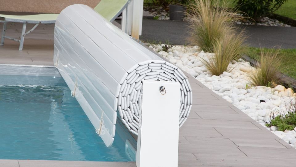 A medence mellett álló fehér medencefedél, amely védi a vizet a szennyeződésektől és csökkenti a párolgást.