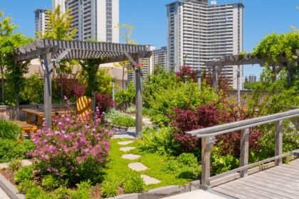 Egy városi tetőkert, tele virágokkal és zöld növényekkel, háttérben modern épületekkel.