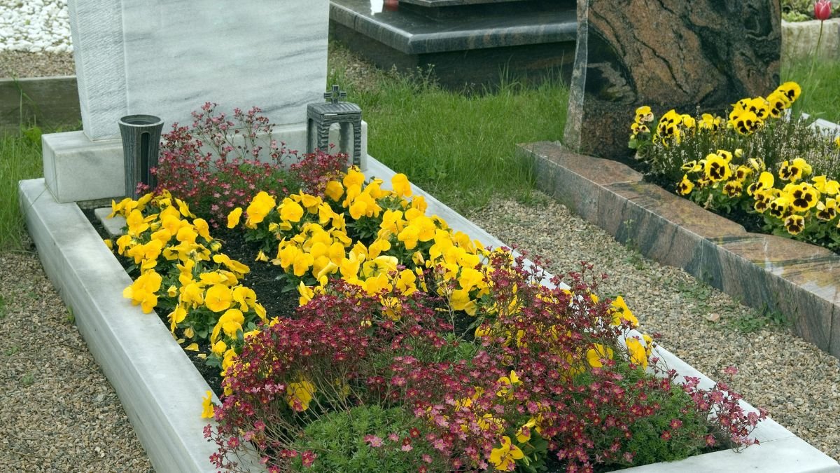 Színes árvácskák és piros virágok díszítik a sírt, barátságos és emlékezetes légkört teremtve.